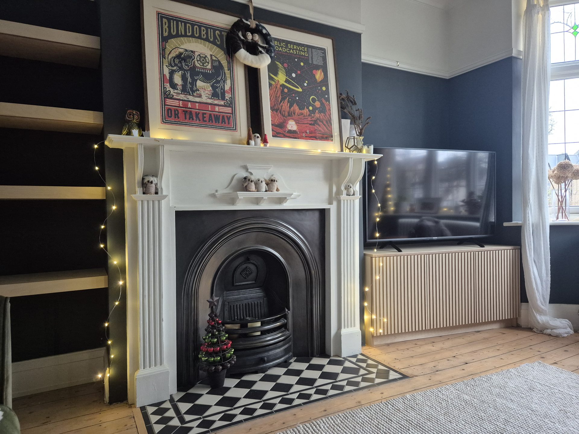 Dark navy fireplace alcove with shelving and television