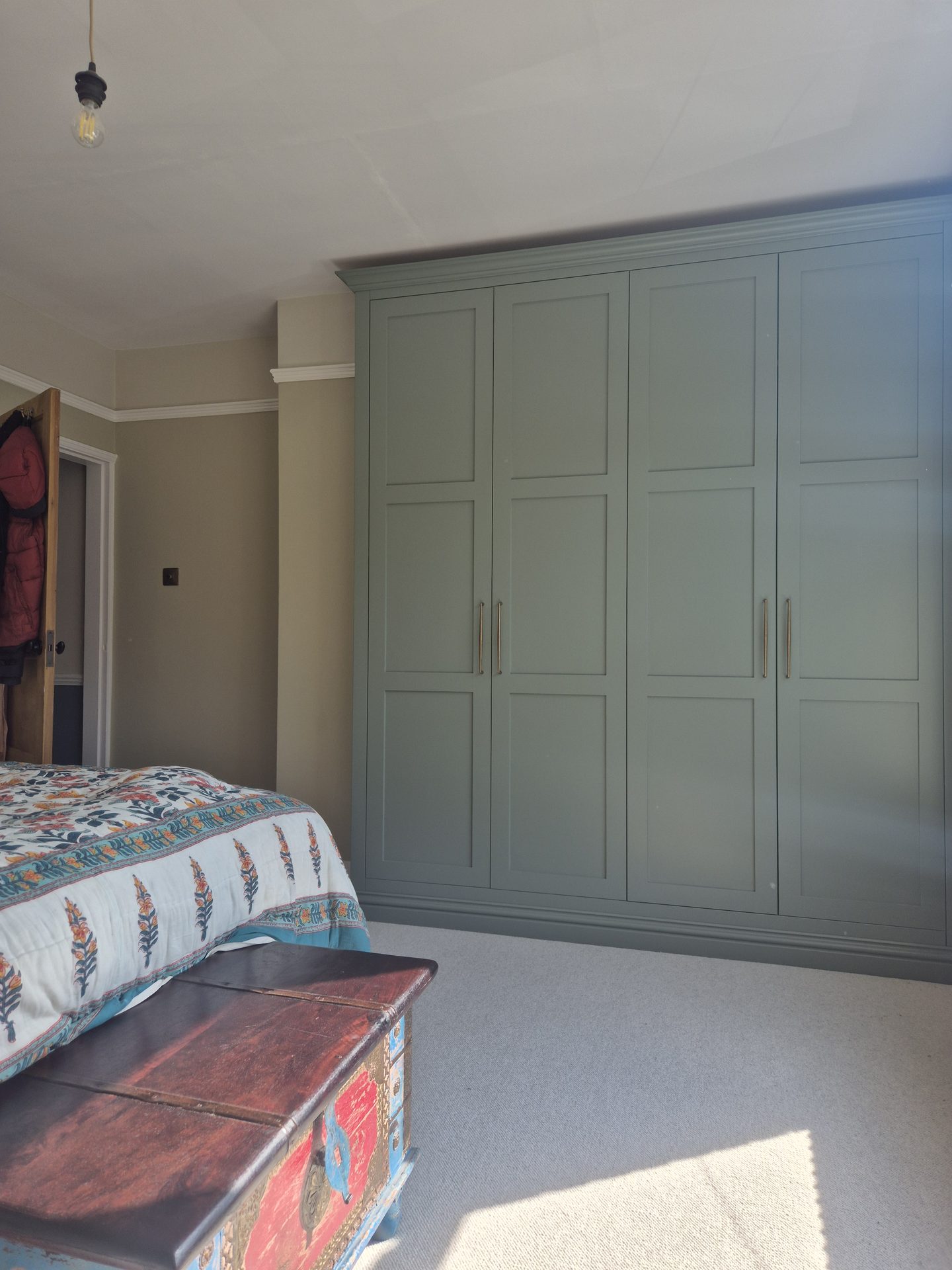 Sage green fitted wardrobe wall in a bedroom